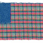 A rectangular woven textile reminiscent of the American flag, with a solid blue rectangle in the upper left corner where the stars usually are and a blue, pink, and green plaid pattern where the stripes would be.