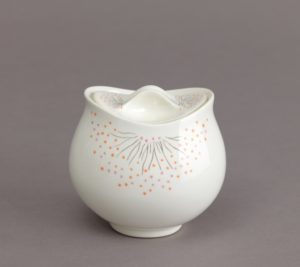 Smooth, white sugar bowl in a curving shape vaguely reminiscent of a rose, decorated with clusters of thin black lines surrounded by explosions of tiny pink and orange dots like bunches of delicate flowers.
