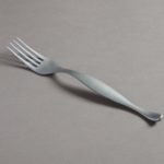 A matte, silvery fork with a delicately arched handle that bulges out slightly in the center.