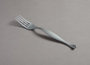 A matte, silvery fork with a delicately arched handle that bulges out slightly in the center.