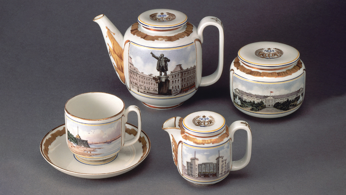 A four-piece porcelain tea set decorated with highly-detailed depictions of different landmarks in Leningrad and accented with ornate gold designs.