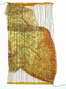 A large crumpled swatch of partially translucent yellow fabric is suspended amongst a loom-like pattern of long vertical threads.