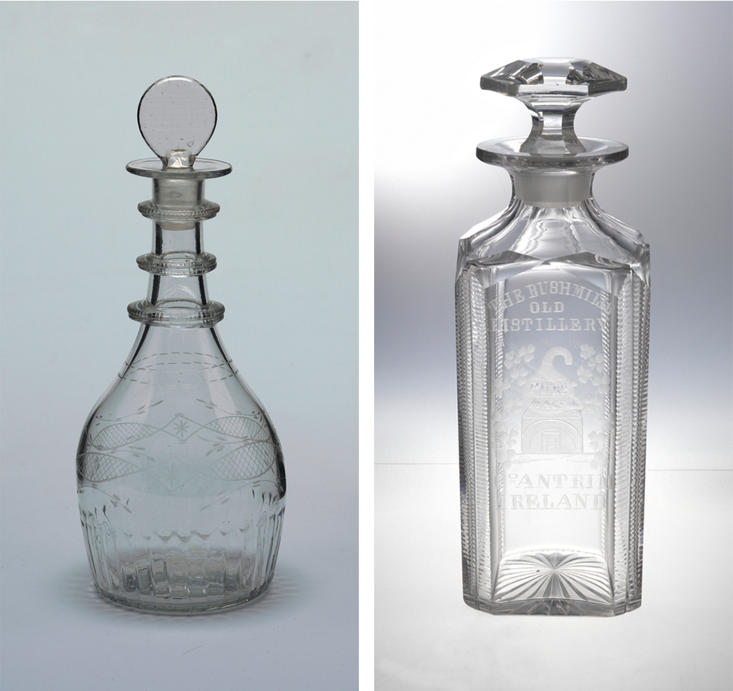 A clear, colorless decanter with a bulbous bottom ascending into a narrow-necked top and a disc-like stopper next to another clear, colorless decanter in a blocky form with decorative details and capped with a faceted stopper.