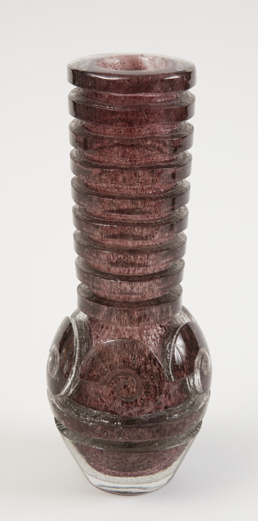Cylindrical brown speckled vase with ovular base and long neck with horizontal rows of indentations creating a textured spiral or coiled effect.