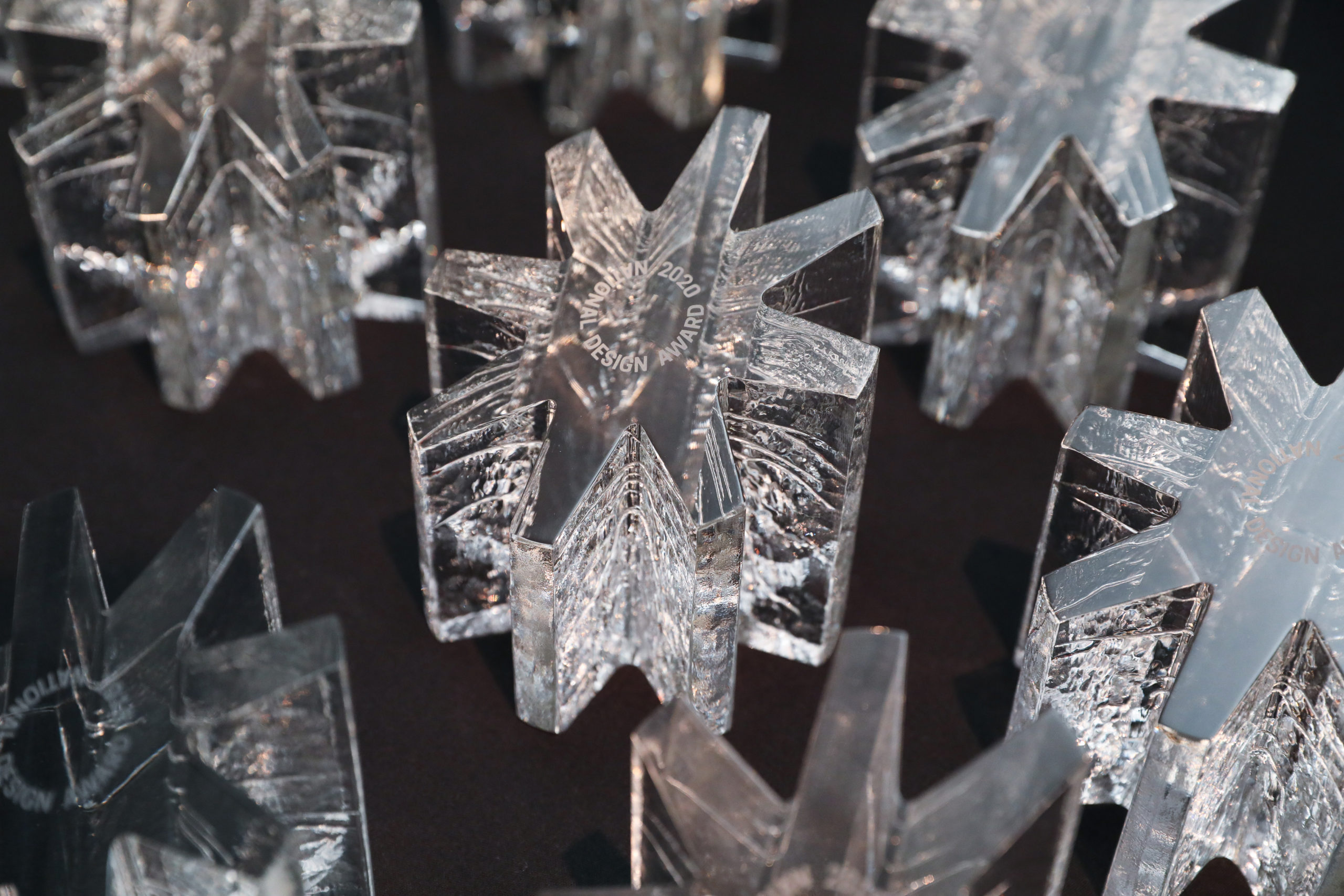 A group of transparent, colorless, starburst-shaped glass trophies sit on a black background.