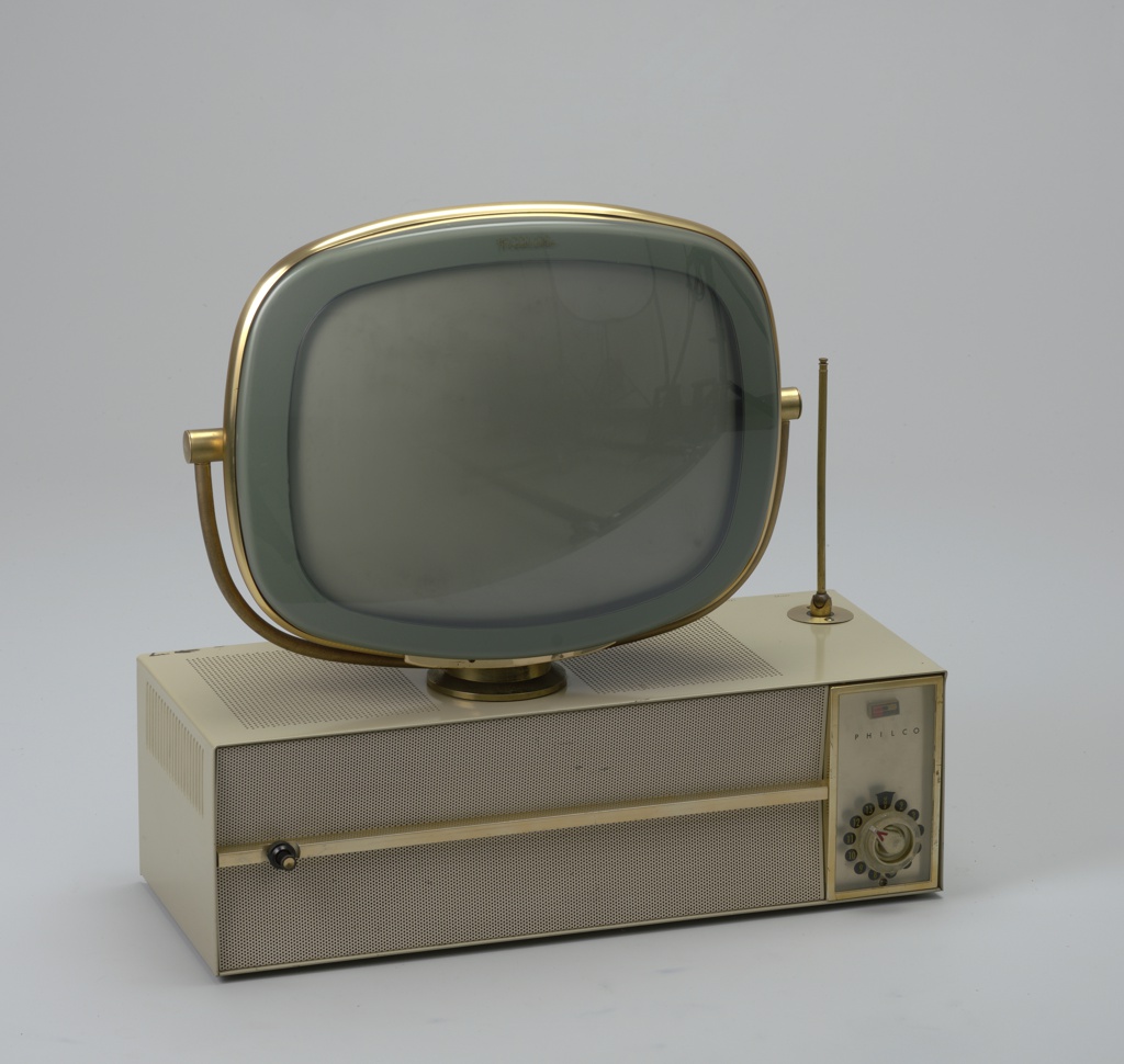 A round-cornered gray television screen suspended on a rounded brass bracket. The bracket is centered on a beige, rectangular platform.