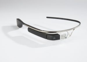 Eyeglass-like frame with a simple band on the left earpiece and on the right earpiece a glass prism and plastic housing for a camera and other technical elements.