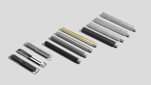 A collection of eleven uniquely-shaped specialty pens in solid colors including gray, black, and gold.