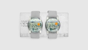 Two identical watches with digital numbers, clear circle watch faces, and light gray bands.