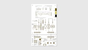 A white circuit board with small holes throughout and brown writing and patterns.