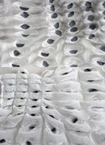 A close up photo of white fabric that is textured with a oval pattern.
