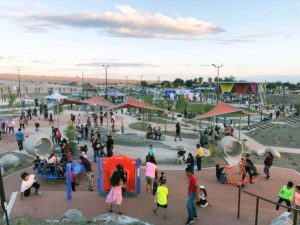 A photograph of many children playing in a playground within a desert landscape.