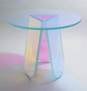 Glass table formed by a circular top on tripod base composed of three angled, oval legs. Glass iridizes and changes color depending on angle of view.