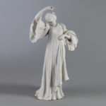 A porcelain figurine of a person with their head tilted and their body gracefully posed wearing a long, flowing robe.