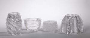 Four transparent, colorless glass vessels of different shapes but relatively similar sizes.