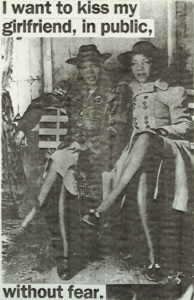 A small gray-scale poster picturing two women in hats and coats sitting on a bench; above and below them is the text “I want to kiss my girlfriend, in public, without fear.”