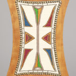 Close-up view of the back of a wooden chair, a rectangular shape with concave edges and, embedded into it on deer hide, glass beads in white, brown, blue, red, green, and orange forming graphic abstract shapes.