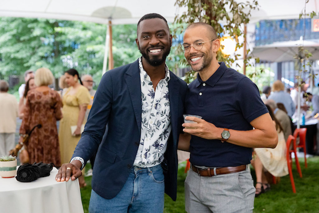 Two Cooper Hewitt staff members smile together in the Cooper Hewitt garden.