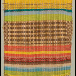 A large, woven, textured fabric with stripes of earthy colors and metallic accents.