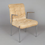 A chair with chrome arms and legs and woven beige upholstery.