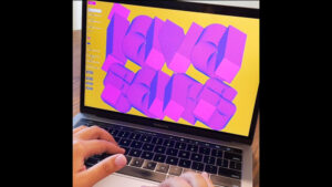 A close-up image of a laptop and hands on the keyboard, with purple and yellow graphic typology on the screen.