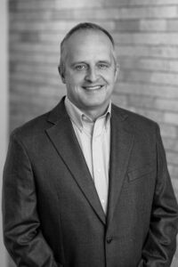 Black and white headshot portrait of man in a suit.