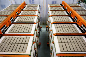 Photograph of vertically stacked rectangular tiles on platforms in factory setting.