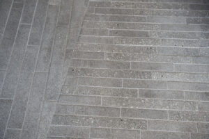 Photograph of grey rectangular tiles, with a central diagonal line dividing vertical tiles on the left and horizontal tiles on the right.