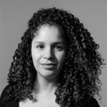 Black and white portrait of Christina L. De León who has curly hair and is wearing a black shirt.