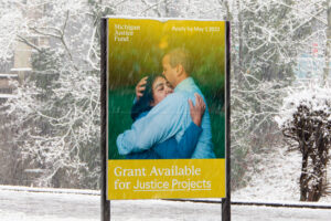 A publicly displayed advertisement poster of the Michigan Justice Fund depicting a photo of two people hugging.