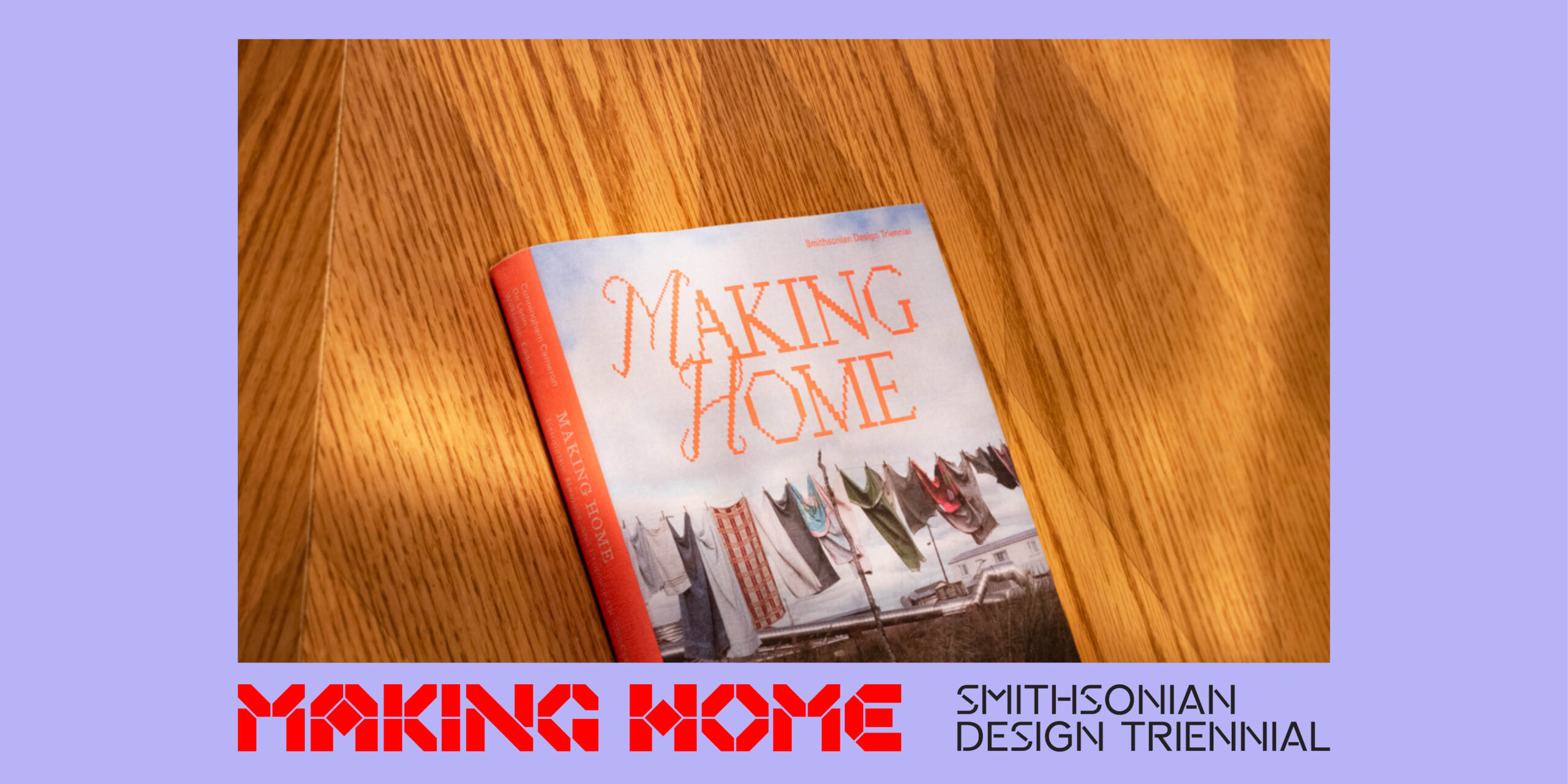 An up-close image of a book titled "Making Home." The cover art is of a clothes line with various items hung up. The title text is orange. The book is placed on a wood table. The image is bordered in light purple. At the bottom, red text reads "Making Home." Black text reads "Smithsonian Design Triennial."