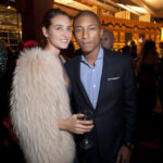 Pharrell Williams and a fellow guest smile and hold drinks at the National Design Awards.
