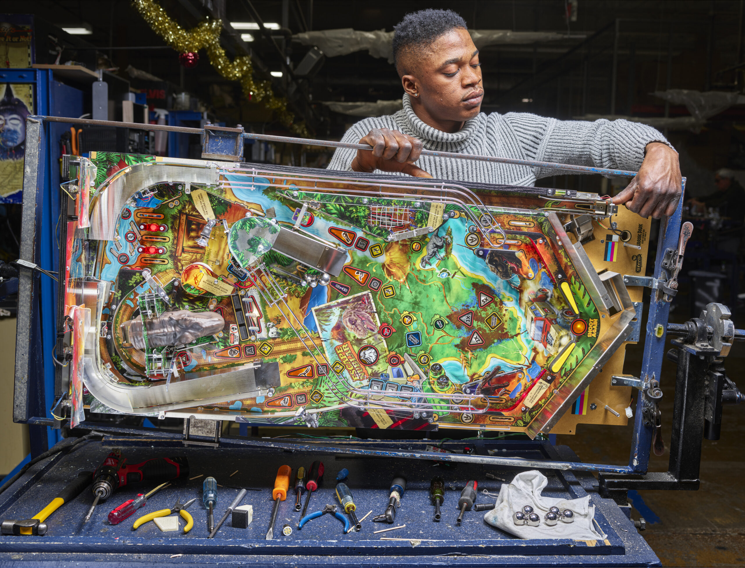 A pinball machine is turned on its side as a worker inspects it