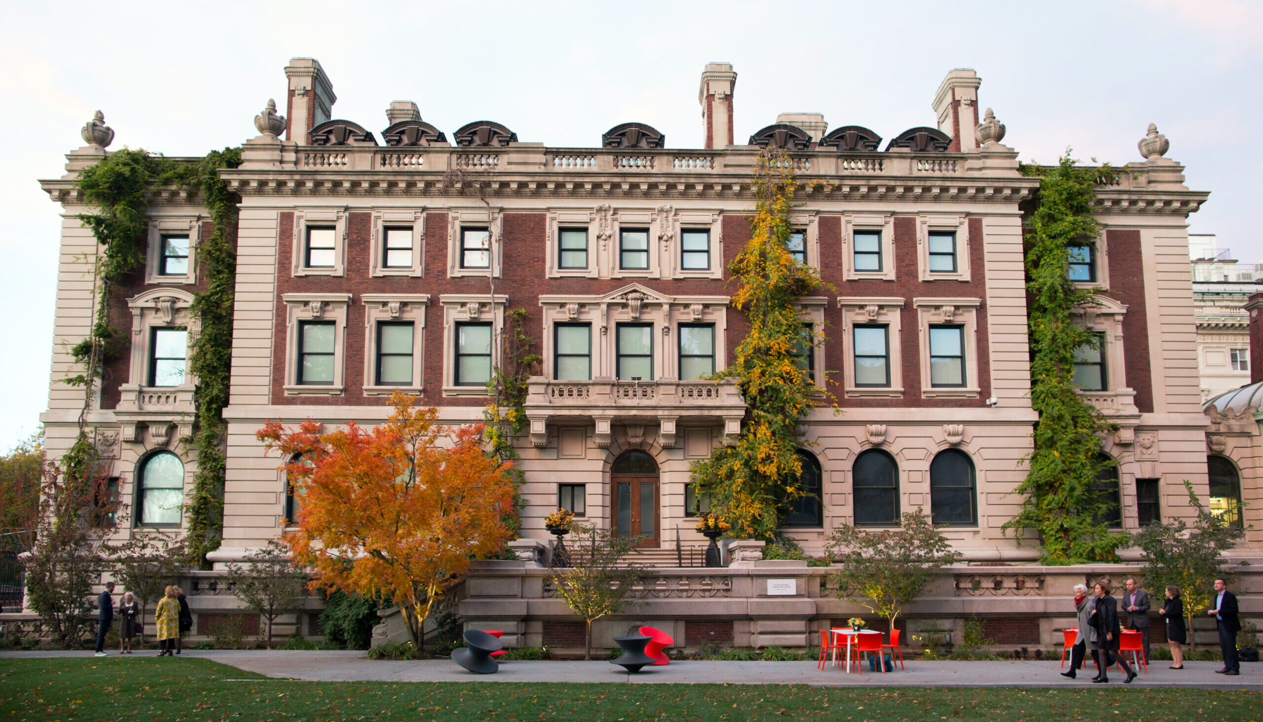 View of exterior of Cooper Hewitt Smithsonian Design Museum from the garden in fall with orange leaves on the trees