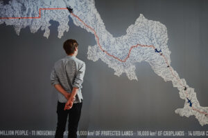 Person standing in front of a large wall map showing river networks and highlighted route.