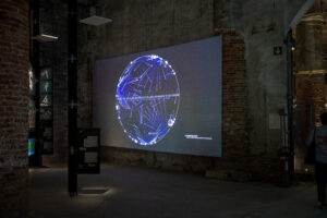 Dark industrial room with a large screen showing a white circle with bright blue lines radiating from white dots