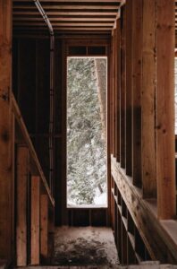 A view from inside of a wood-paneled structure facing a tall rectangular window to the snowy outside.