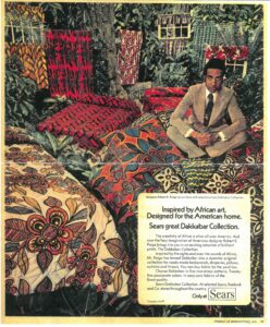 Magazine ad showing a man in a suit sitting on bedding, curtains, and pillows with bold African inspired patterns