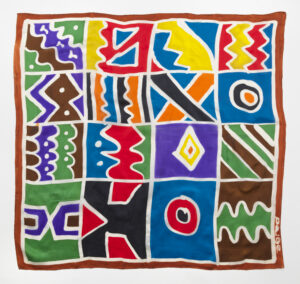 Colorful textile featuring a grid of abstract shapes, zigzag patterns, circles, and bold lines.