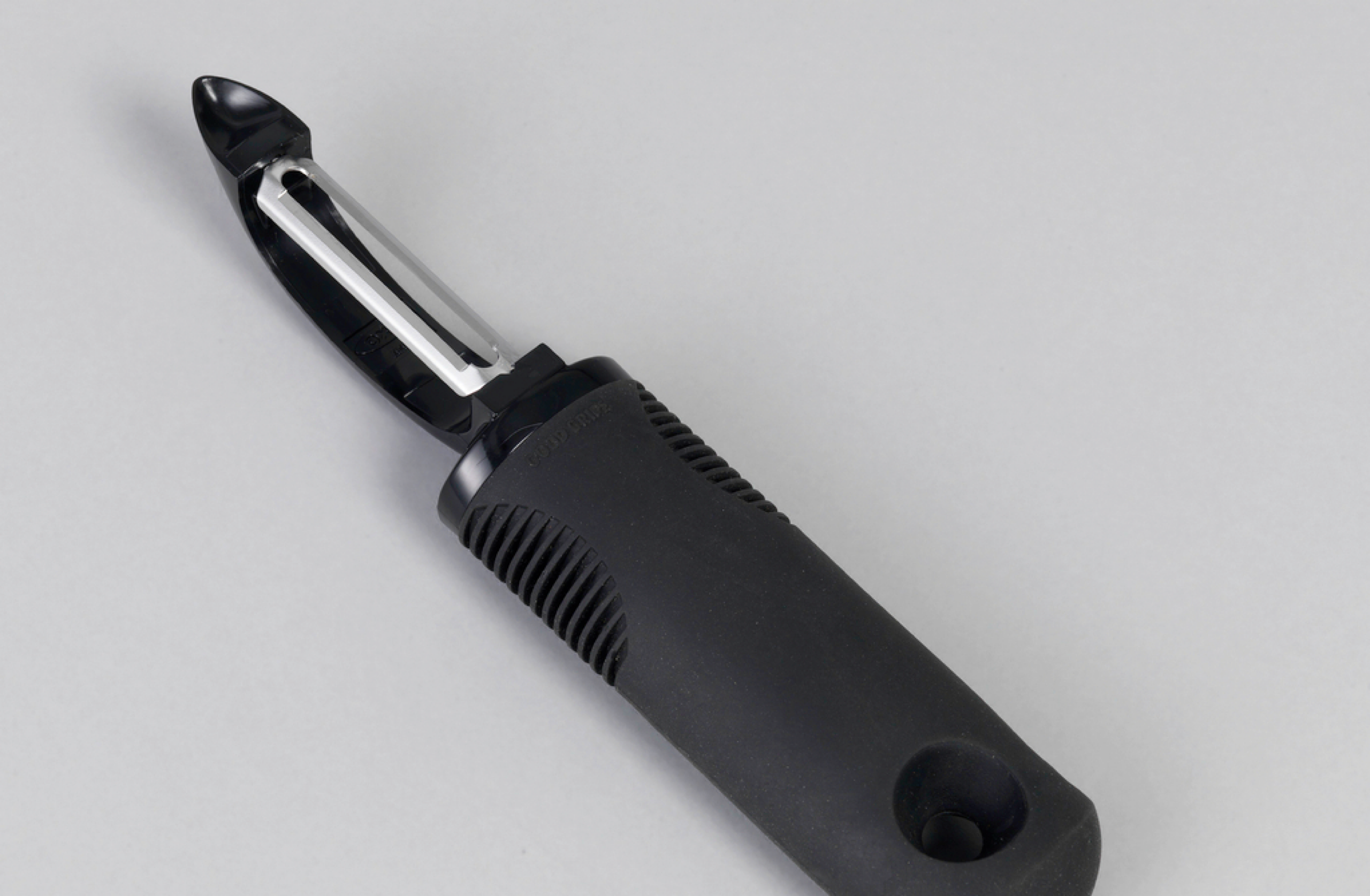 Photograph of a metal peeler with a black handle.