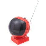 A red helmet shaped television with a square base with control knobs and an antenna at the top.