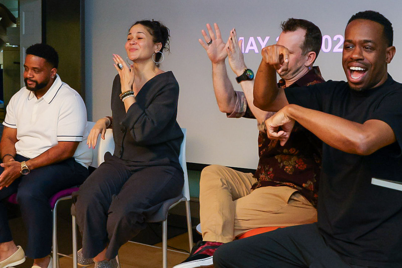 Four people on a stage using American Sign Language to address an unseen audience.